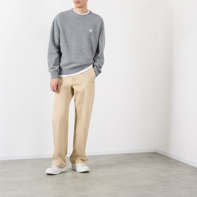 Model wearing Loewe beige casual cotton trousers, styled with a grey sweatshirt and white trainers.