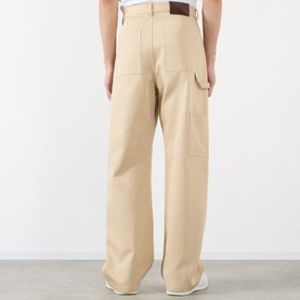 Model wearing Loewe beige cotton casual trousers, rear view, wide-leg fit with contrast stitching and utility pocket detail.