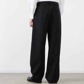 Model wearing Loewe black wide-leg wool casual trousers, styled with a white shirt and black leather shoes, back view.