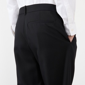 Model wearing Loewe black wool casual trousers, close-up of rear waistband and back pocket, styled with white shirt