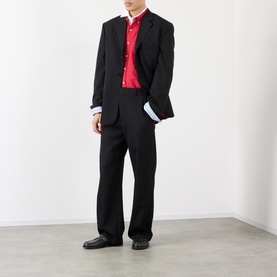 Model wearing Loewe black wool casual trousers with matching black blazer, red shirt and black loafers.