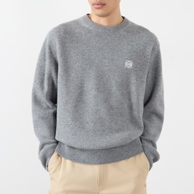 Model wearing Loewe Anagram Logo Sweater in grey melange, crew neck wool knit with chest logo embroidery, styled with beige trousers
