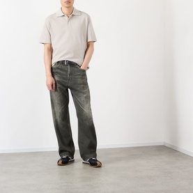 Model wearing Loewe grey cotton polo shirt with open collar, styled with dark washed jeans and black trainers.