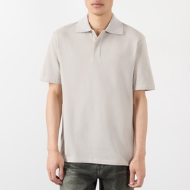 Model wearing Loewe grey cotton polo shirt with open collar, styled with dark jeans