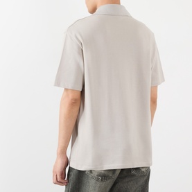 Model wearing Loewe grey cotton polo shirt, back view, short sleeves, with distressed denim jeans