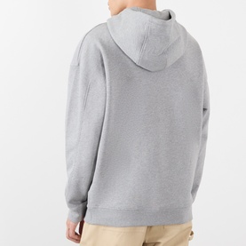 Model wearing Loewe grey melange cotton hoodie, rear view showing hood and relaxed fit, styled with beige trousers
