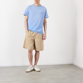Model wearing Loewe beige cotton shorts with blue crew-neck T-shirt and white trainers.
