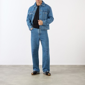 Model wearing Loewe Anagram Logo Baggy Jeans in jeans blue, mid-rise straight-leg fit with Anagram knee detailing, styled with denim jacket and black