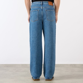Model wearing Loewe Anagram Logo Baggy Jeans in jeans blue, mid-wash denim, five-pocket styling, tobacco stitching, rear view