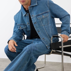Model wearing Loewe Anagram Logo Baggy Jeans in jeans blue, mid-wash denim with straight leg, styled with matching denim jacket and black top.