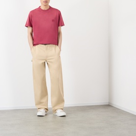 Model wearing Loewe red cotton T-shirt with small chest logo, styled with beige wide-leg trousers and white trainers.