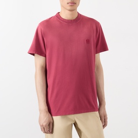 Model wearing Loewe red cotton T-shirt with tonal logo patch at chest, styled with beige trousers