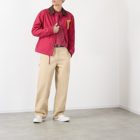 Model wearing Loewe red cotton jacket with brown collar and tan pocket detail, styled with beige wide-leg trousers and white trainers
