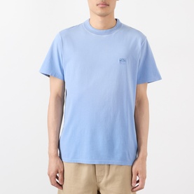 Model wearing Loewe Tonal Anagram Logo T-Shirt in blue, crew neck, short sleeves, tonal chest embroidery, styled with beige trousers.