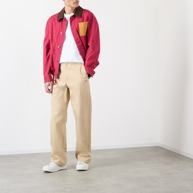 Model wearing Loewe white cotton T-shirt, styled with red colour-block overshirt, beige wide-leg trousers and white trainers.