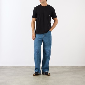 Model wearing Loewe black cotton crew-neck T-shirt, styled with mid-blue wide-leg jeans and dark loafers.