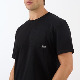Model wearing Loewe black cotton T-shirt with chest pocket and small embroidered Anagram logo, crew neck, short sleeves.
