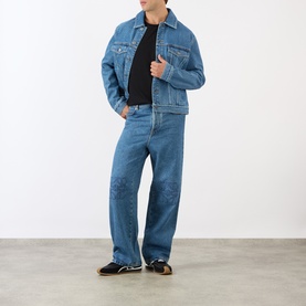 Model wearing Loewe black T-shirt styled with mid-blue denim jacket and matching jeans, black loafers