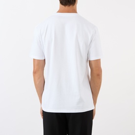 Model wearing Loewe Anagram Logo Chest Pocket T-Shirt in white, rear view, with black trousers. Short sleeves, straight hemline.