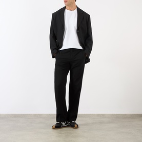 Model wearing Loewe Anagram Logo Chest Pocket T-Shirt in white, styled with black blazer, black trousers and dark trainers.