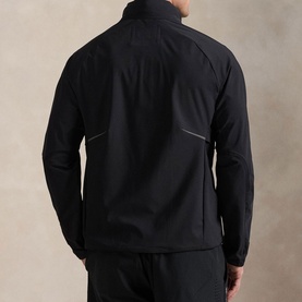 Model wearing RLX Golf black casual jacket, rear view, with matching black trousers. Zip pockets and reflective details visible.