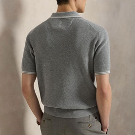 Model wearing RLX Golf knit polo in Spring Heather, rear view, short sleeves with contrast tipping, paired with tailored trousers.