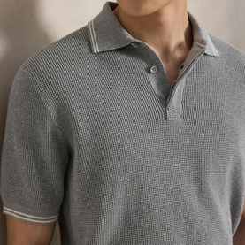 Model wearing RLX Golf knit polo in Spring Heather and Stone Pebble, with tipped collar and button placket detail