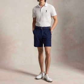 Model wearing RLX Golf light green polo shirt with navy shorts and white shoes