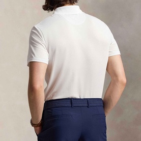 Model wearing RLX Golf light green polo shirt, back view, styled with navy trousers