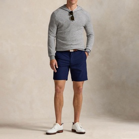 Model wearing RLX Golf shorts in Refined Navy, styled with a grey hoodie, white leather shoes and sunglasses.