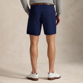 Model wearing RLX Golf shorts in Refined Navy with brown belt, styled with white trainers, rear view.