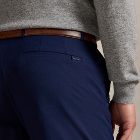 Model wearing RLX Golf shorts in Refined Navy, styled with a grey knit sweater and tan leather belt, close-up rear detail view