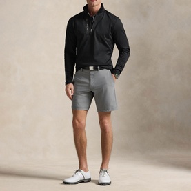 Model wearing RLX Golf black quarter-zip pullover with grey shorts and white golf shoes