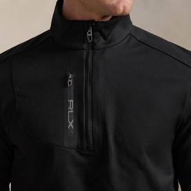Model wearing RLX Golf black quarter-zip sweat, close-up of chest zip pocket and branded logo detail on smooth technical fabric.