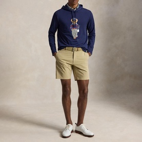 Model wearing RLX Golf Refined Navy Polo Bear graphic hoodie, styled with khaki shorts and white golf shoes.
