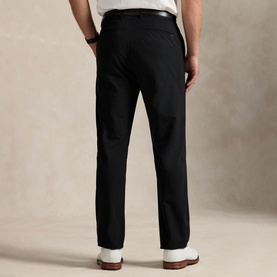 Model wearing RLX Golf trousers in Polo Black, rear view, styled with a white T-shirt, black belt, and white trainers.
