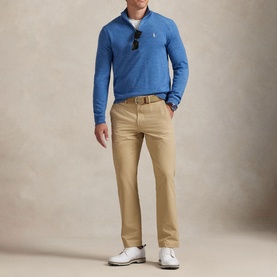 Model wearing RLX Golf beige trousers with a blue quarter-zip top and white trainers, styled with a tan belt.