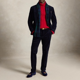 Model wearing navy corduroy blazer and trousers with red cable-knit turtleneck, plaid scarf, tan belt, and navy loafers