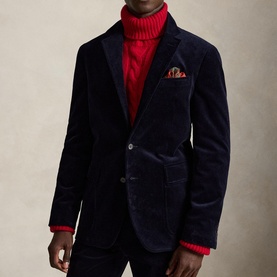 Model wearing navy corduroy blazer with two-button front and pocket square, styled with a red roll-neck jumper