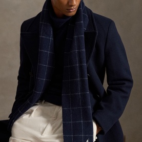 Model wearing navy wool overcoat with navy windowpane check scarf, styled with cream trousers