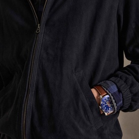 Model wearing Ralph Lauren collection navy suede casual jacket, zip front, hand in pocket, styled with blue watch on brown strap.