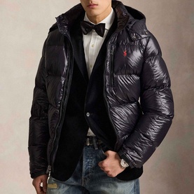 Model wearing Ralph Lauren Polo Black Glossy casual jacket with red pony logo, styled over blazer with bow tie and jeans.
