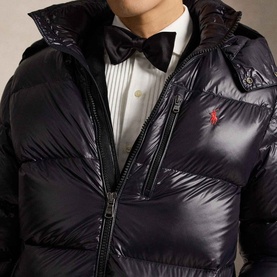 Model wearing Ralph Lauren Polo Black Glossy quilted down jacket with red pony logo, styled over white dress shirt and black bow tie.