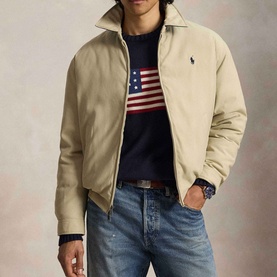 Model wearing Ralph Lauren khaki casual jacket with zip front, styled with navy American flag jumper and blue jeans.