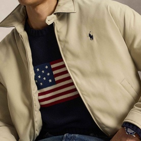Model wearing Ralph Lauren khaki casual jacket, layered over a navy American flag knit sweater with blue jeans visible.