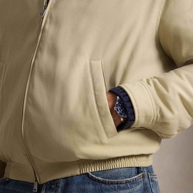 Model wearing Ralph Lauren khaki casual jacket, close-up of side pocket detail, styled with blue jeans and navy watch.