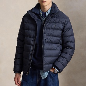 Model wearing navy quilted puffer jacket with zip fastening and embroidered logo, styled with blue denim shirt and jeans