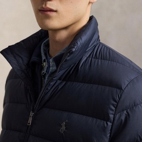 Model wearing navy quilted puffer jacket with funnel neck and zip fastening, styled over a blue chambray shirt