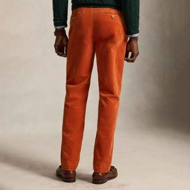Model wearing Ralph Lauren Pony Logo Straight Leg Corduroy Trousers in Charles Orange, rear view, styled with green knit and brown shoes.