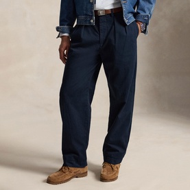 Model wearing Ralph Lauren aviator navy pleated chino trousers, styled with a denim jacket and tan suede loafers.